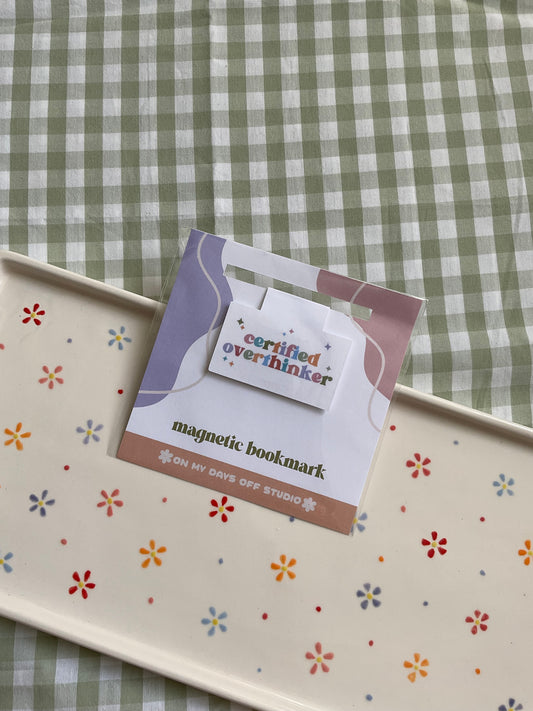 Magnetic bookmark with a rainbow text saying "Certified Overthinker" with cute stars around it