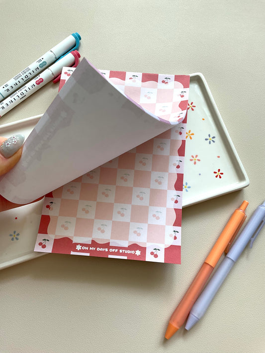 Red and pink checkered notepad with cute little cherries in the pink boxes of the print