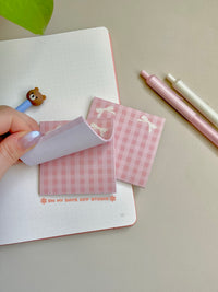 Pink girly themed sticky notes with two beige bows in the top corners