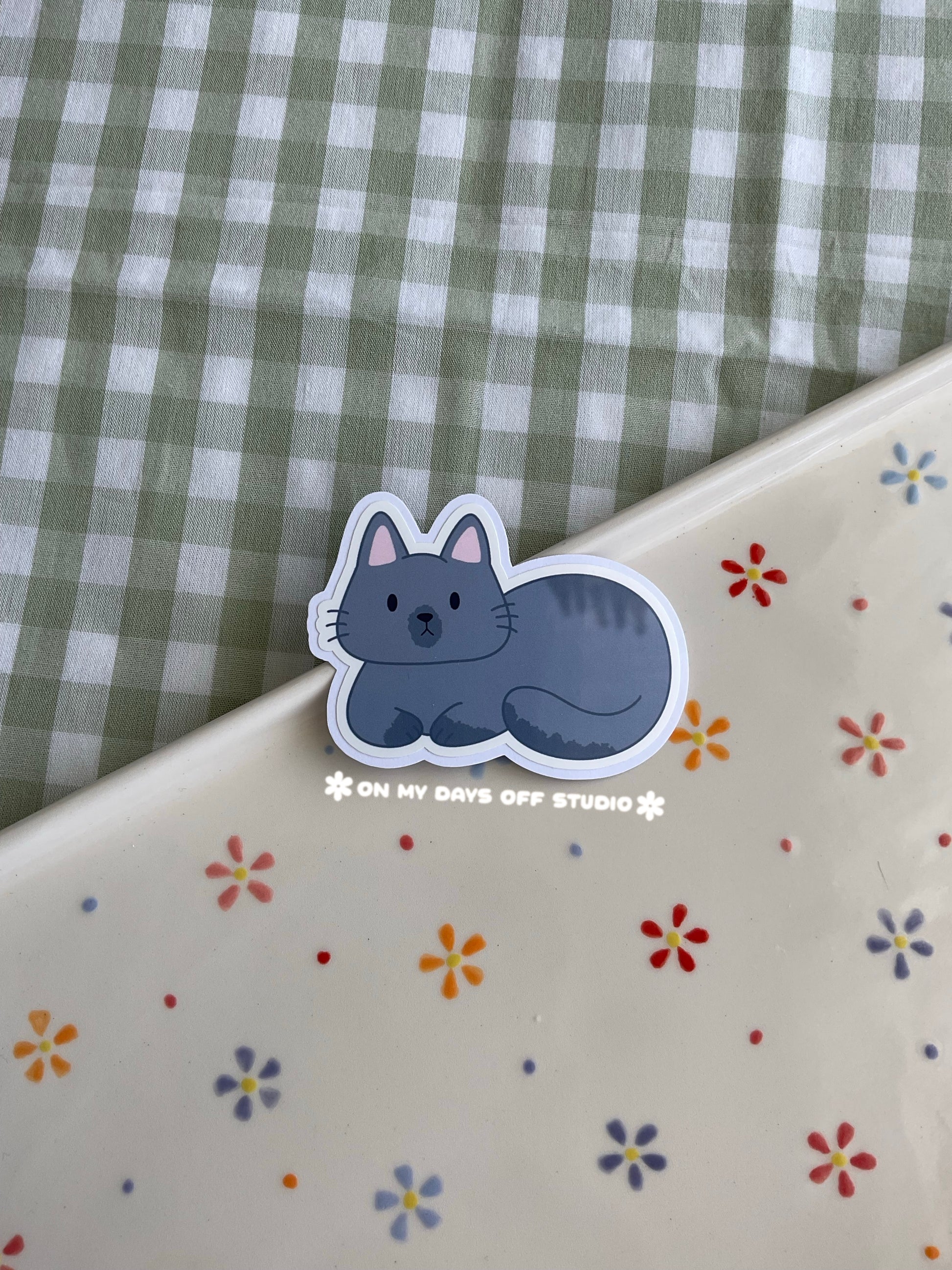 Cute vinyl sticker of a cute grey cat curled up 