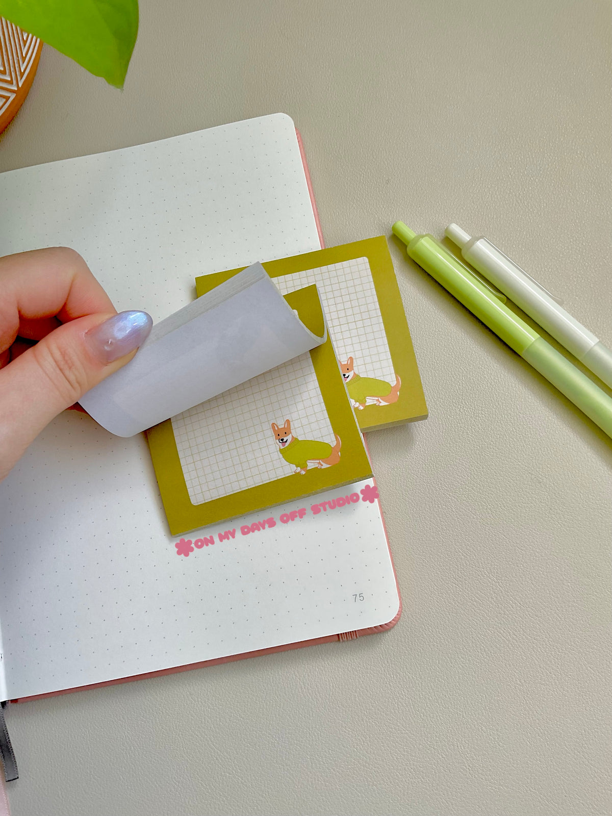 Green boarder sticky note with a beige grid background and a corgi in the right corner wearing a sweater