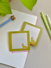Green boarder sticky note with a beige grid background and a corgi in the right corner wearing a sweater