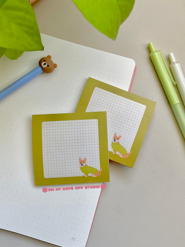 Green boarder sticky note with a beige grid background and a corgi in the right corner wearing a sweater