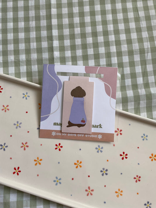 Cute poodle magnetic bookmark but turned around to show it's cute purple sweater with cherries in the bottom corner