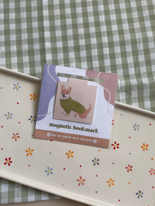 Magnetic Bookmark with a beige background and corgi wearing a green sweater