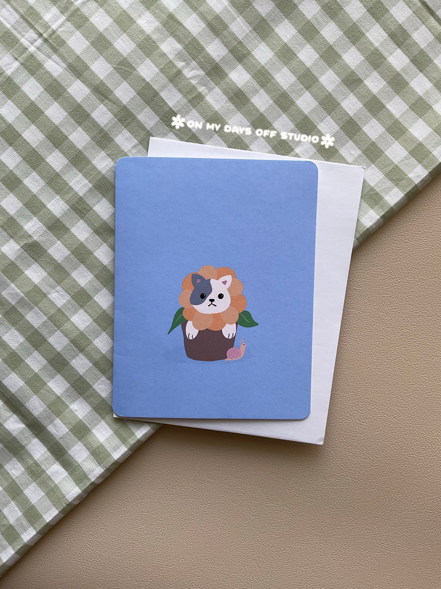 Blue greeting card with a cute cat in a floral pot.