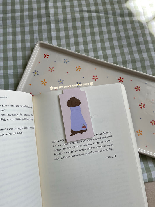 Cute poodle magnetic bookmark but turned around to show it's cute purple sweater with cherries in the bottom corner