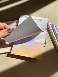 Cute beige notepad with a fun sunset cloud illustration at the bottom half. Brain Dump is noted in purple at the top. 