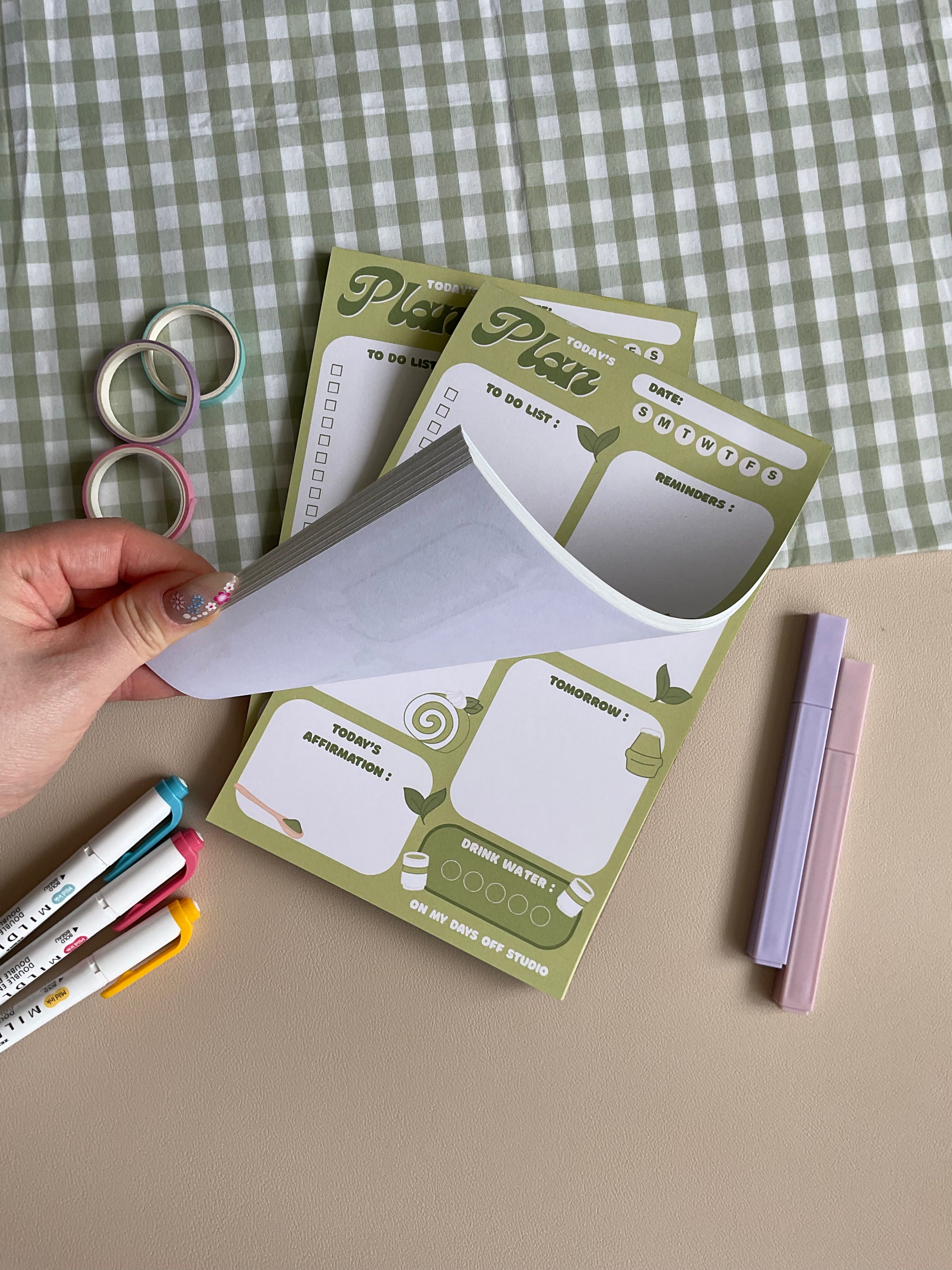 A daily planner notepad with a matcha theme, featuring illustrations of matcha drinks and leaves. It has sections for a t do list, reminders, tomorrow list, today's affirmation and water in take tracker.