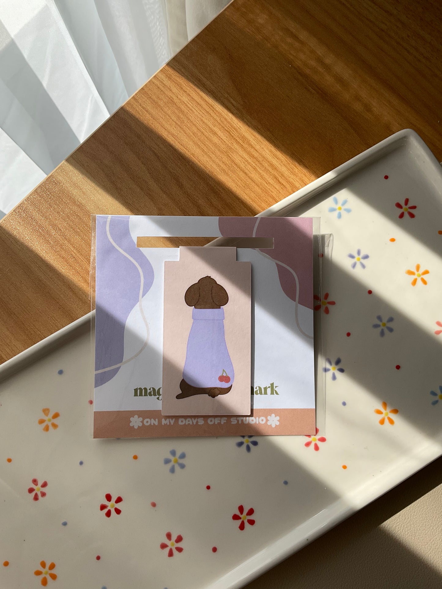 Cute poodle magnetic bookmark but turned around to show it's cute purple sweater with cherries in the bottom corner