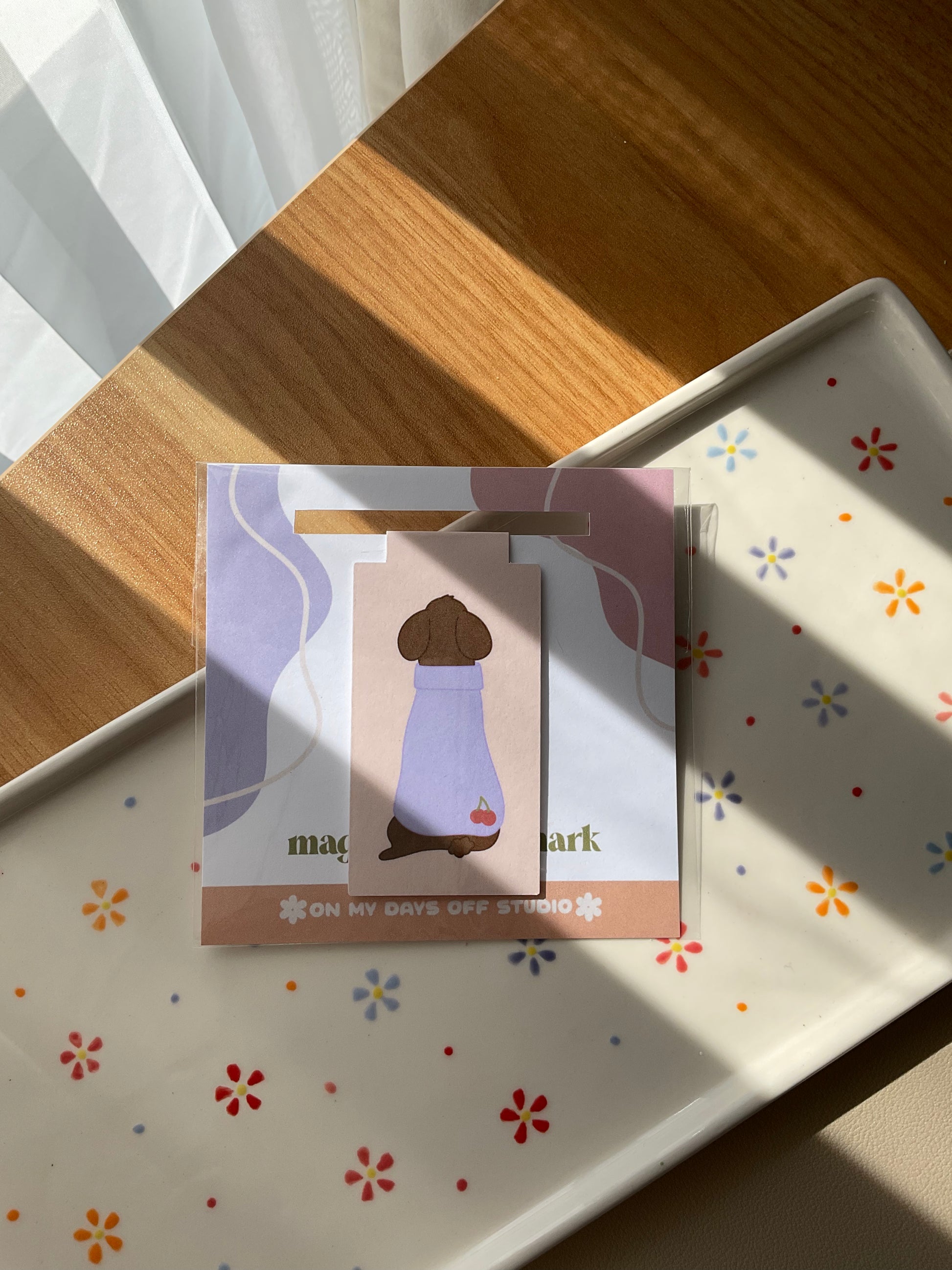 Cute poodle magnetic bookmark but turned around to show it's cute purple sweater with cherries in the bottom corner
