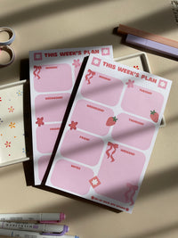 Weekly planner with a pink, red, bow and strawberry theme. It has sections for every day of the week and for notes.