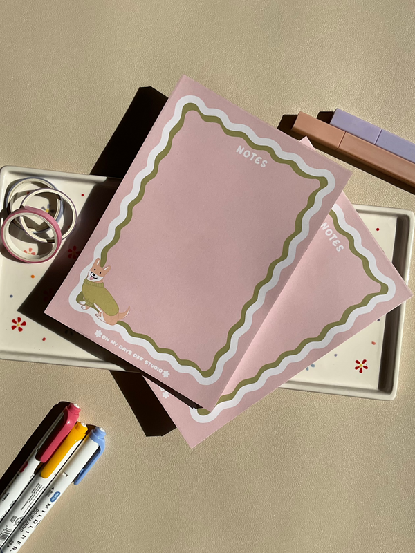 Cute light pink notepad with a retro wavy boarder in white and green. A cute corgi in a green sweater sitting in the bottom left corner