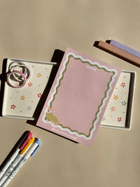 Cute light pink notepad with a retro wavy boarder in white and green. A cute corgi in a green sweater sitting in the bottom left corner