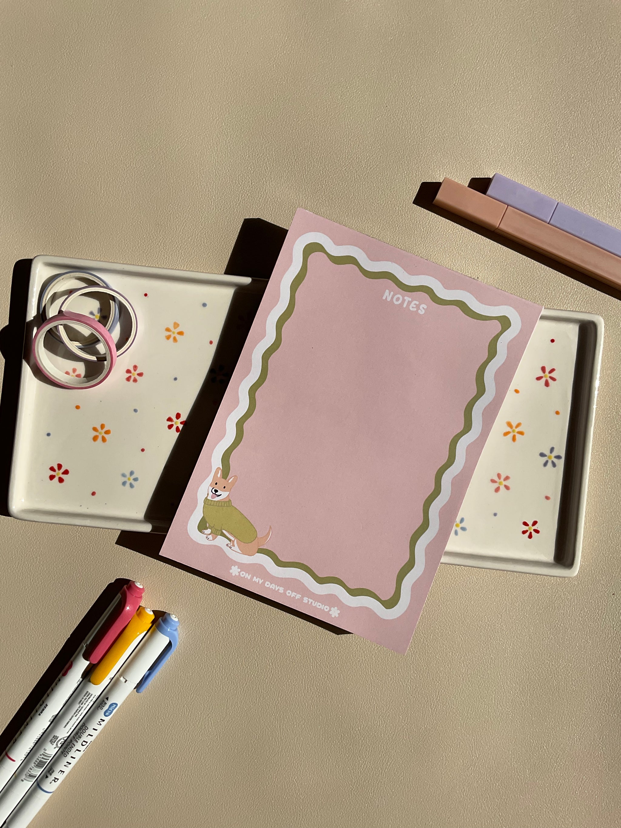 Cute light pink notepad with a retro wavy boarder in white and green. A cute corgi in a green sweater sitting in the bottom left corner