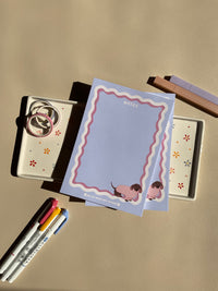 Cute light purple notepad with a retro wavy boarder in white and pink. A cute dachshund in a pink sweater sitting in the bottom right corner