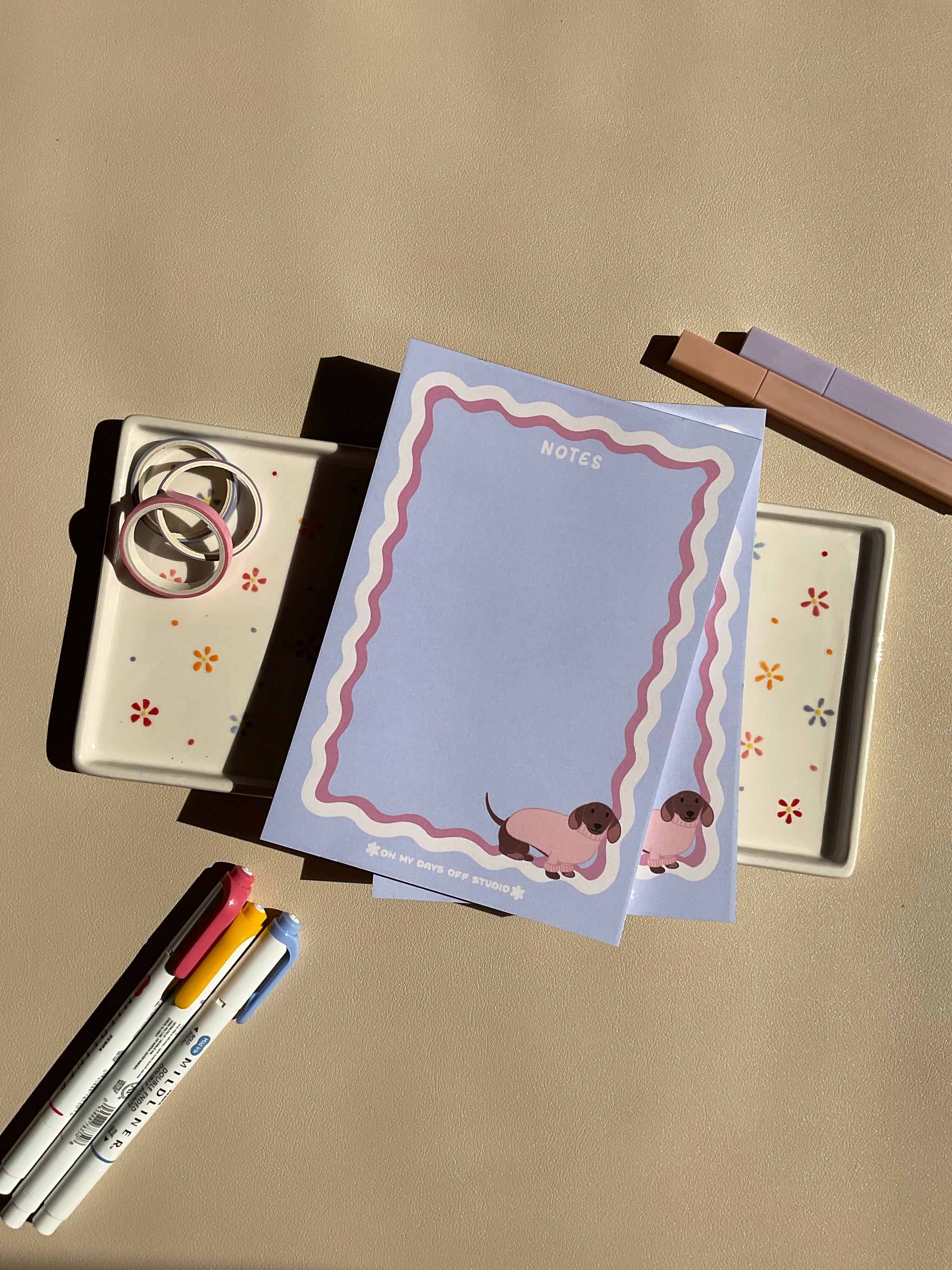 Cute light purple notepad with a retro wavy boarder in white and pink. A cute dachshund in a pink sweater sitting in the bottom right corner