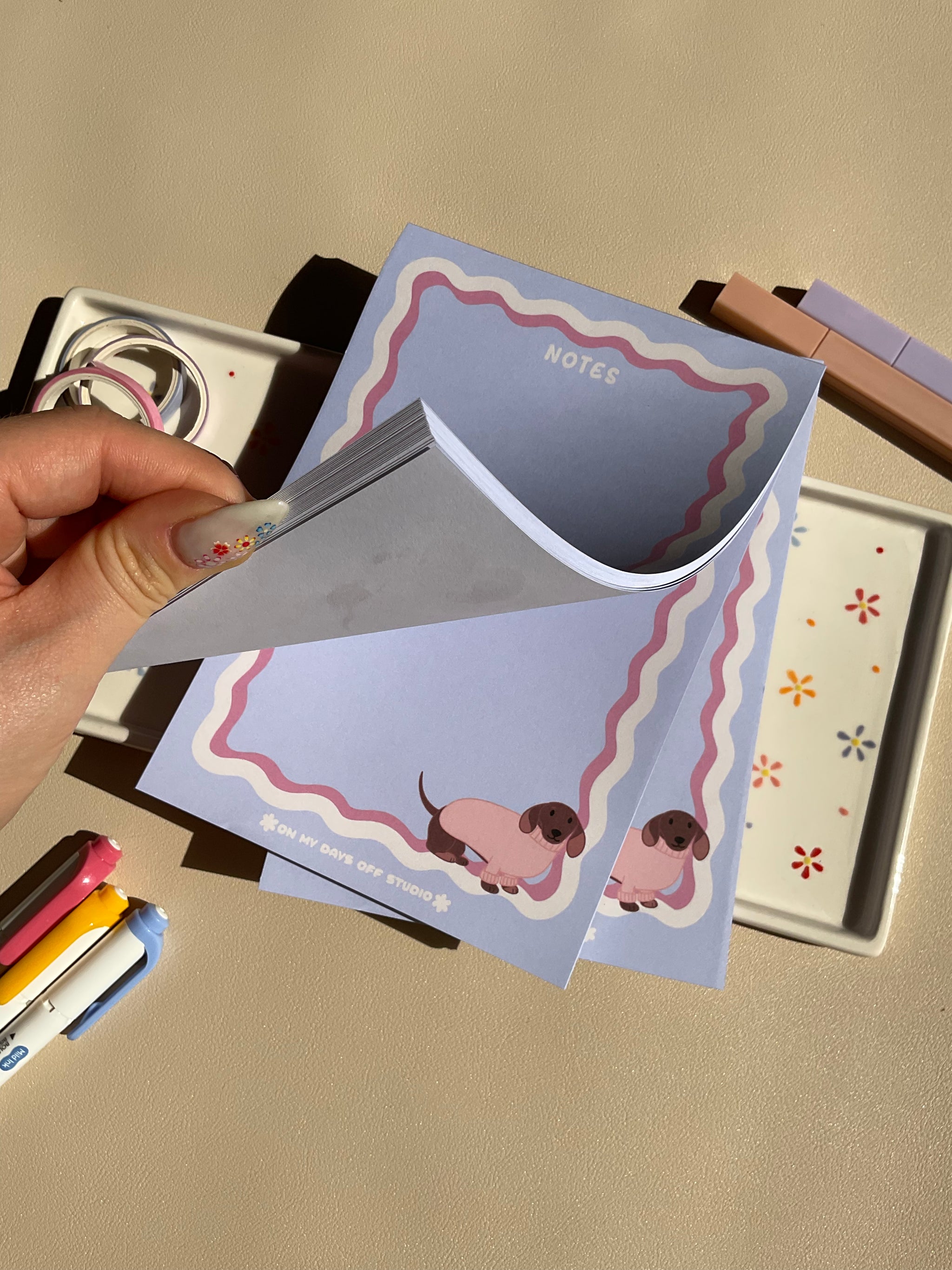 Cute light purple notepad with a retro wavy boarder in white and pink. A cute dachshund in a pink sweater sitting in the bottom right corner