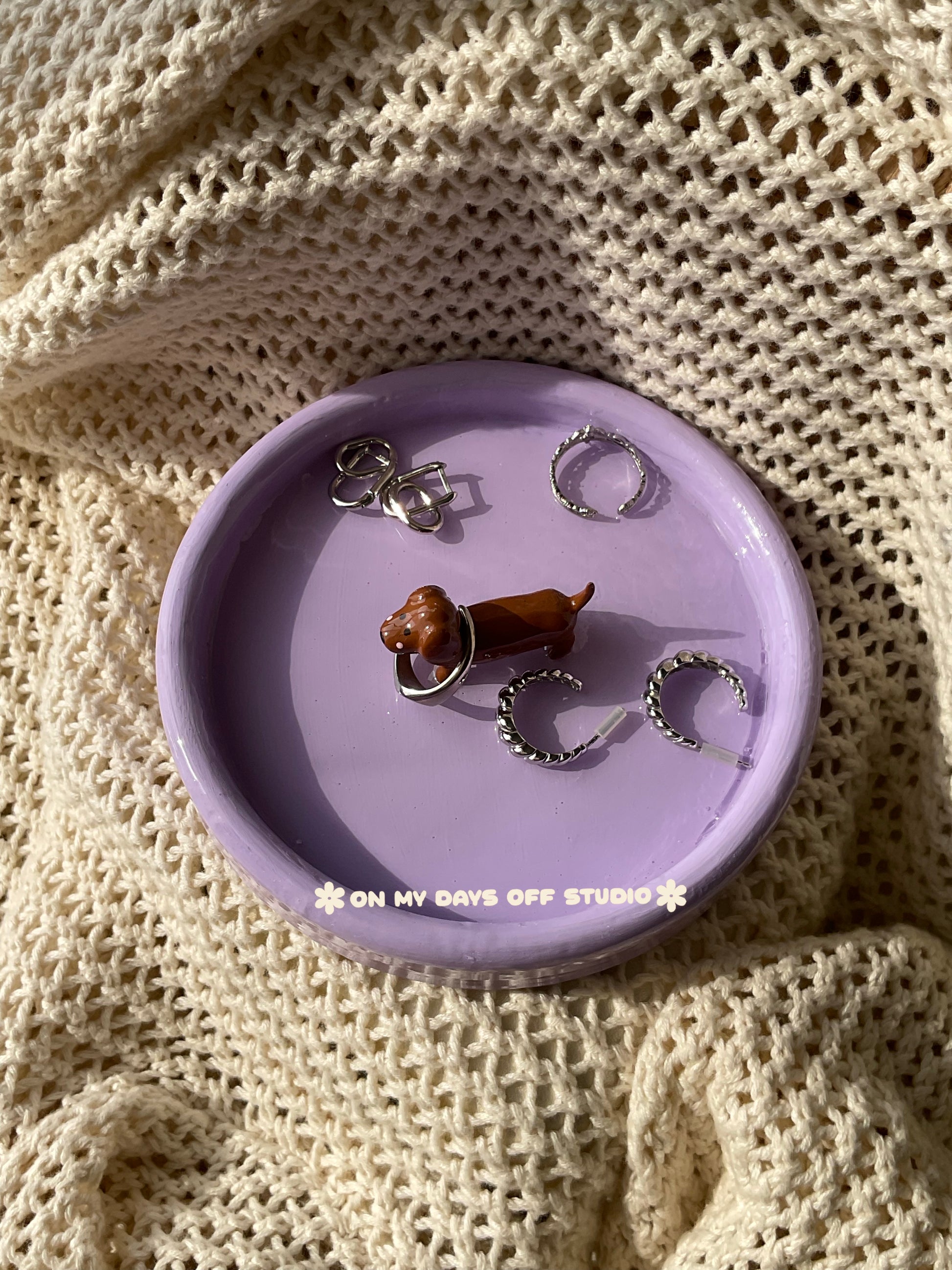 Small brown dachshund figurine on a purple jewelry dish or trinket dish