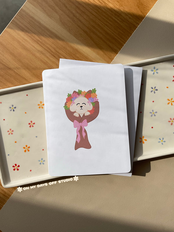White greeting card with a cute illustration of a puppy in a bouquet of flowers. Blank interior for your personal handwritten message. 