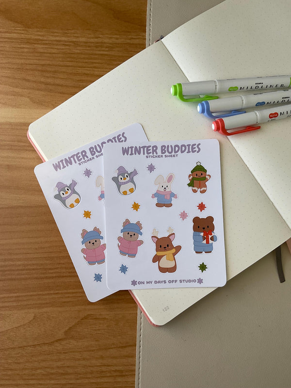 winter buddies sticker sheet front, featuring 6 illustrations of cute animals wearing winter clothes and accessories. This includes a penguin, bunny, gingerbread man, bear, deer and dog. Also, it includes 6 colorful stars. 